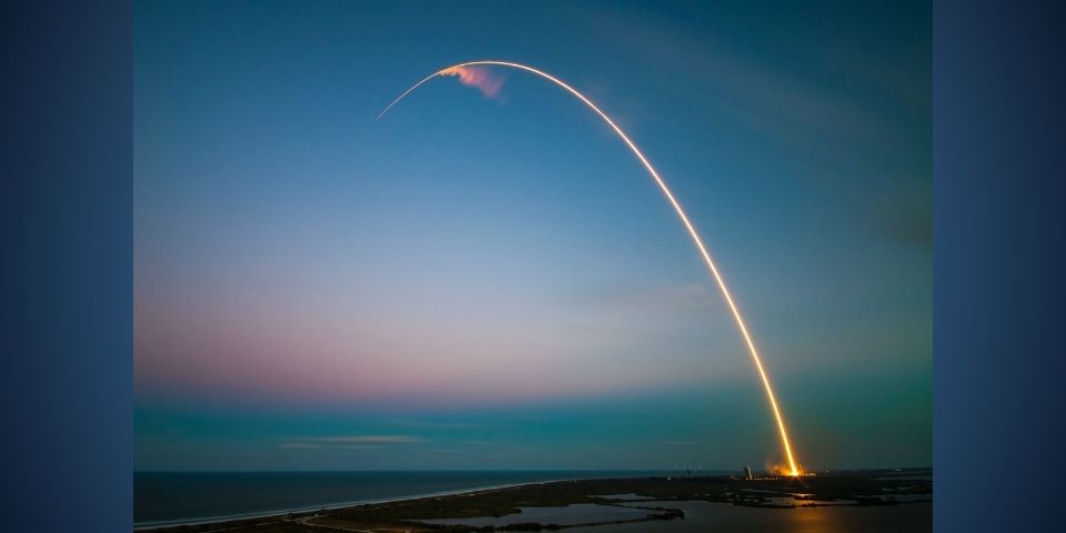 rocket night launch over body of water