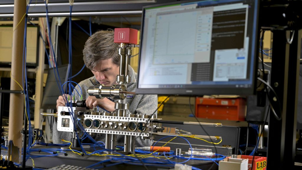 research physicist from the U.S. Naval Research Laboratory (NRL) Quantum Optics Section attaches fiber-optic cables to deliver light into the compact laser-delivery system