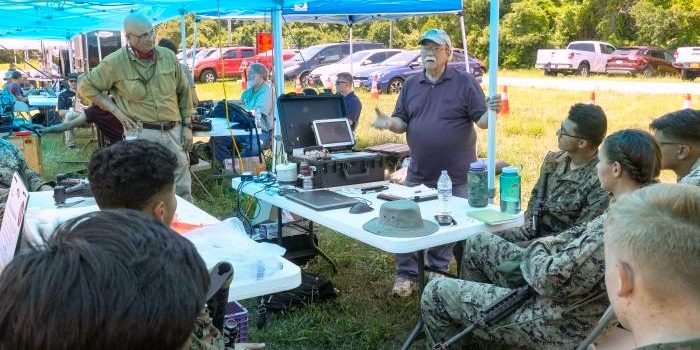 Peter DeSalva (standing, left), an ONR subject matter expert and support contractor, and Dr. John Tucker (standing, right), a Naval Research Laboratory physicist, teach Marines about the Portable Fluid Analyzer Plus system during the Technology Operational Experimentation Exercise 2022 at Camp Lejeune, North Carolina. (U.S. Marine Corps photo by Lance Cpl. Jessica J. Mazzamuto)