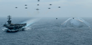 One naval vessel and eleven aircraft traveling over a body of water.