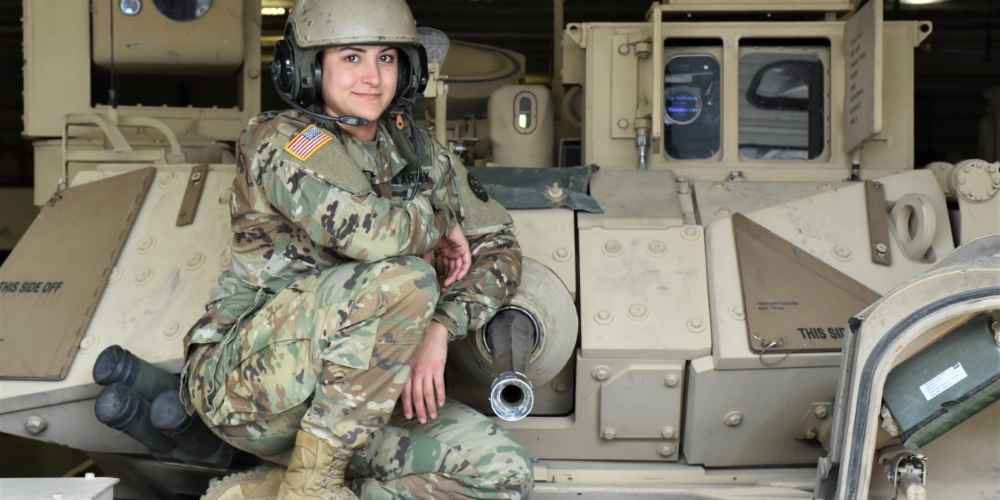 Image of a military servicemember sitting atop a military fighting vehicle.