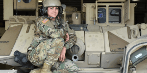 Image of a military servicemember sitting atop a military fighting vehicle.