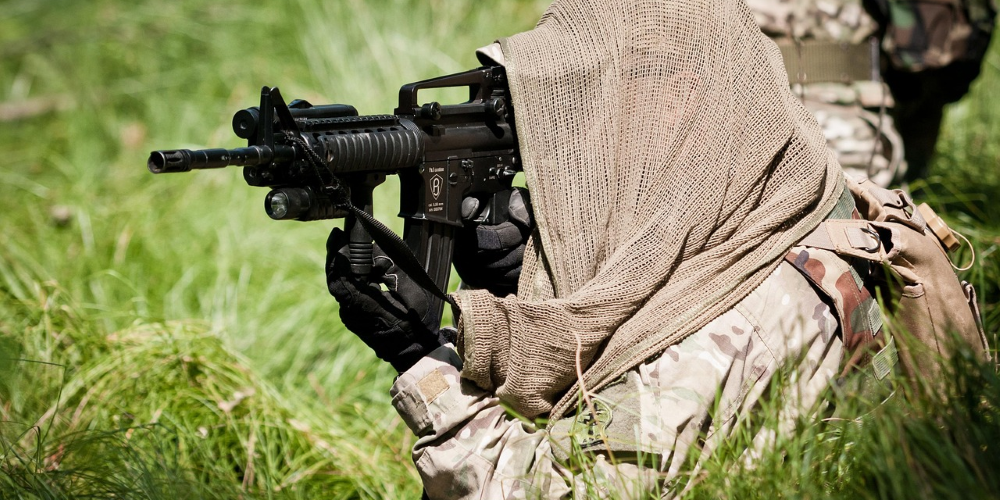 Servicemember with cloth covering over head aiming weapon system.